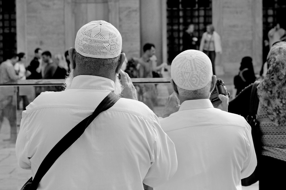 Two men wearing white knitted prayer caps